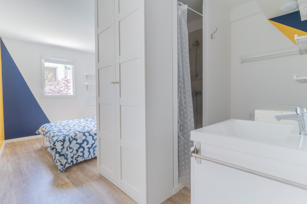 Chambre avec une armoire, un lit double et un évier de salle de bain