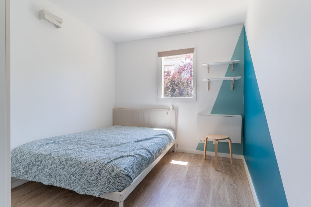 Une chambre avec un lit double, un sol en bois et une fenêtre à l'étage.